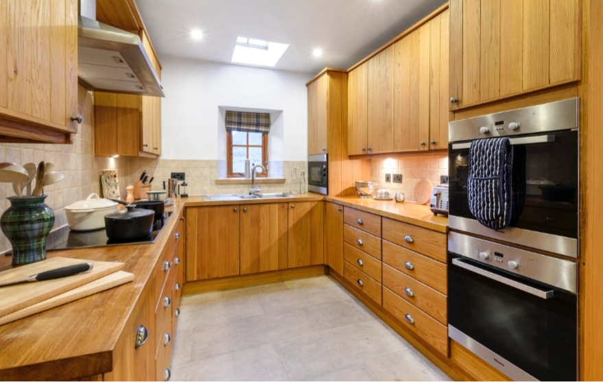 Spacious wooden kitchen, complete with two fitted ovens, induction hob and stone floors.