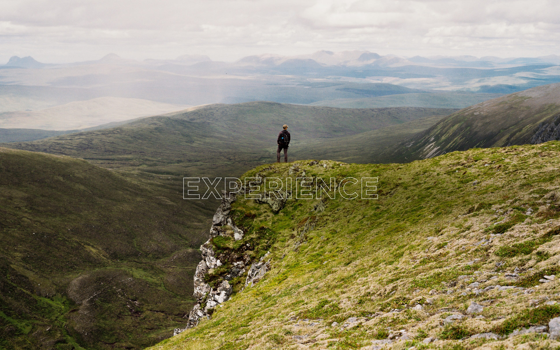 Young adventurer standing at the top of a mountain, overlooking the landscape.