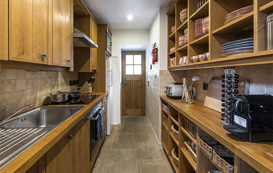 Wooden kitchen with modern appliances including coffee machine, single oven and induction hob.